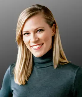Woman with blonde hair wearing a gray turtleneck.