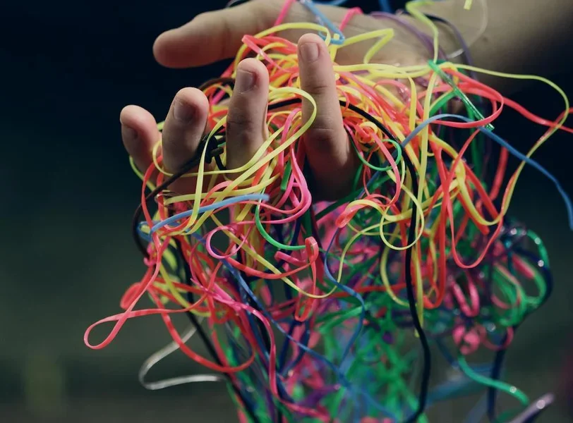 A hand holding a tangled mess of multi-colored string