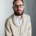 A photograph of Jason Blanda, a 36 year old man with short brown hair, brown eyes, glasses and a tan sweater. 