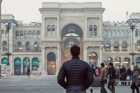 People standing in the courtyard in front of a building, but with most of the people on the left removed.